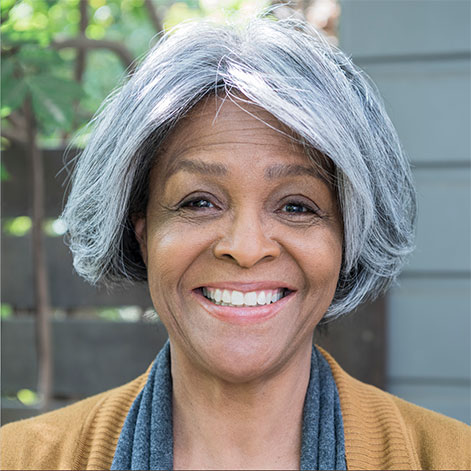 Portrait of an older professional woman with gray hair and a mustard sweater