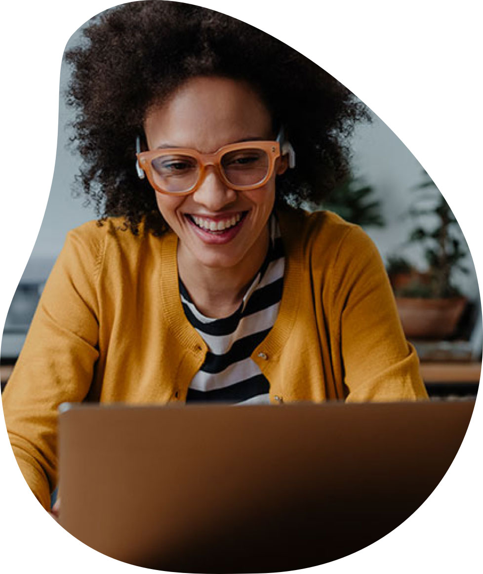 Professional woman with orange glasses smiling and working on her computer